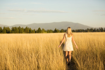 young girl in dress walking in field