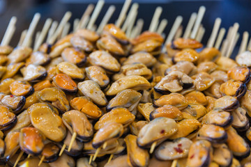 Appetizing skewers of mussels closeup.