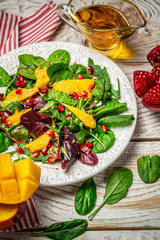 Mango with Pomegranate, lettuce and rocket salad on white plate. Food flat lay. Top view