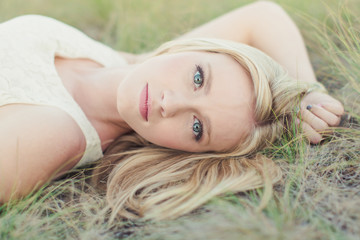 beautiful young woman lying in field looking at camera