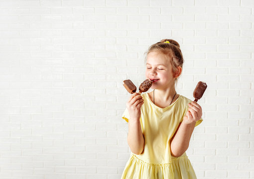 Happy little girl eating chocolate ice cream popsicle at summer time