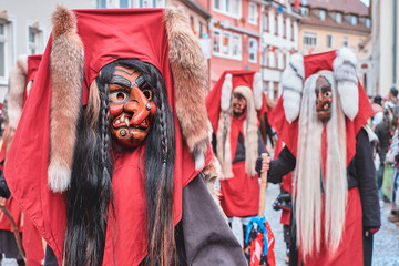 Shrovetide figure with red hood and crooked nose. Street Carnival in Southern Germany - Black Forest.