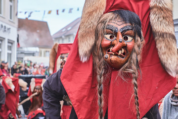 Shrovetide figure with red hood and pigtails. Street Carnival in Southern Germany - Black Forest.