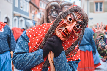 Witch in red blue robe with broom. Street Carnival in Southern Germany - Black Forest.