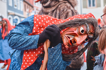 Witch in red blue robe looks at a child. Street Carnival in Southern Germany - Black Forest.