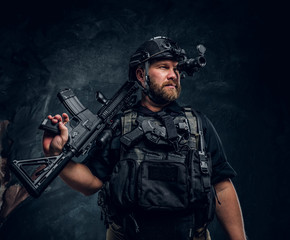 Bearded special forces soldier or private military contractor holding an assault rifle and observes...