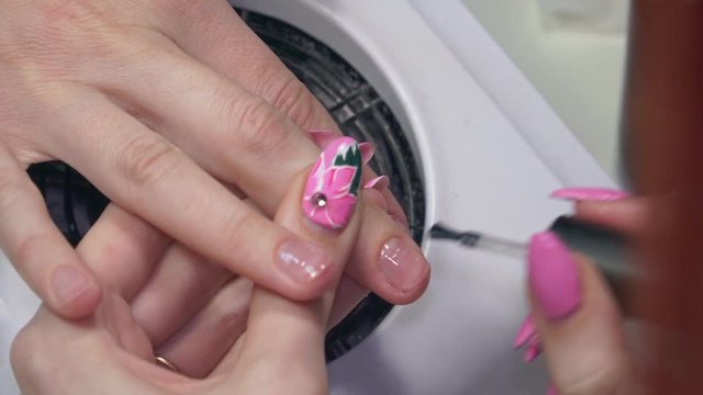 A manicurist paints nails with clear polish