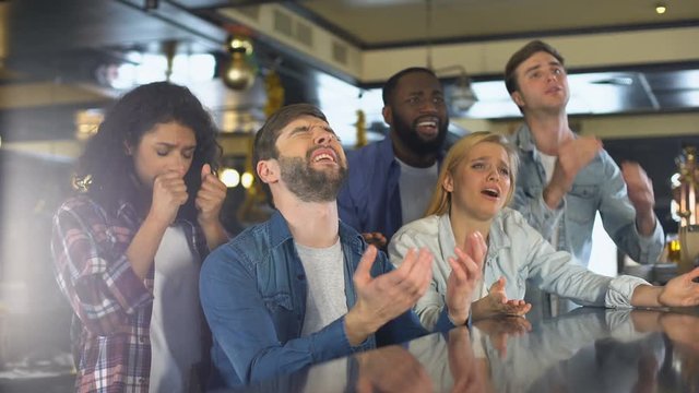 Group of friends watching sports program in bar, upset about losing game, defeat
