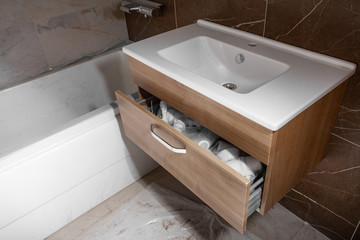 Unfinished Interior of repair and renovation bathroom.  A bathroom remodeling project and design wetroom. Brown marble on the walls. Furniture in protective film.