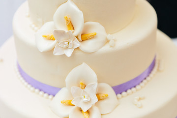Marzipan flowers and purple ribbon on wedding cake