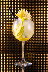 Yellow fruit cocktail with lemon in tall round glass