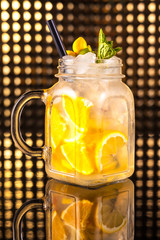 Yellow fruit cocktail lemonade with fresh lemon in vintage jar
