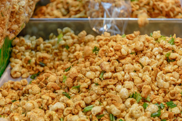 Pile of deep fried or bake pork snack, pork rind, pork scratching or pork crackling on the tray in a market. 
