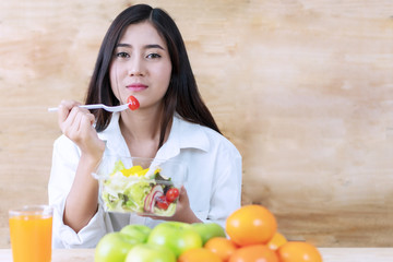 Healthy food concept. Attractive young woman having breakfast with salad vegetarian looking at camera. Smiling girl eating fresh salad for health.