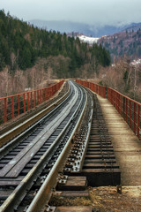 Fototapeta premium empty railway railroad tracks with old vintage wooden ties sleepers leads from viewer to mountains. way path concept. outdoor spring image