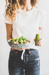 Healthy dinner, lunch. Woman in jeans standing and holding vegan superbowl or Buddha bowl with...