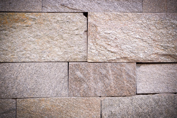 beige weathered stone tiled wall background with vignette. texture.