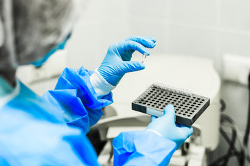 A woman in a sterile lab coat holds in her hand a medical tablet with drugs in white sterile...