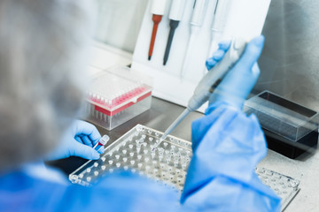 A researcher in a white lab coat collects material in a laboratory syringe batch to place it in a...