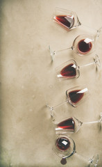 Flat-lay of red wine in glasses over grey concrete background, top view, copy space, vertical...