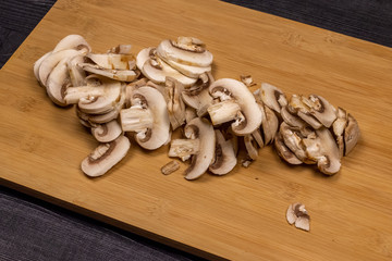 Mushrooms on a cutting board during cleaning and cutting as part of the process of preparing fresh champignons for freezing