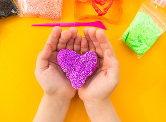 The child sculpts hands of colored clay. Material and tools for creativity.