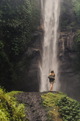 Obraz premium girl stands in front of a huge waterfall