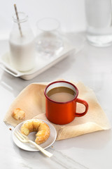 Fototapeta na wymiar Coffee break time table top shot with a mug of coffee and sugary donut on white background.