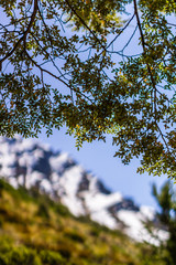peaceful landscape during sunset with calm sky above mountain range, green leaves  in focus