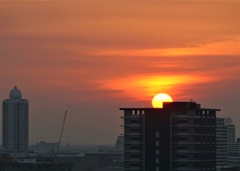 Fototapeta premium Sunset in Bangkok Thailand. Beautiful sun on the top of a building and cityscape with top view on skyscrapers. 
