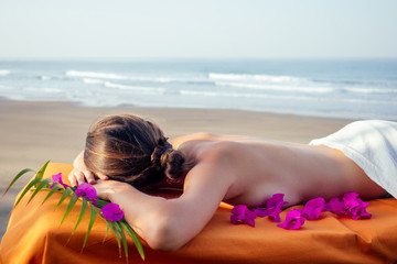 Ayurvedic relaxing massage ,health woman in spa salon getting massage the holiday beach.Beautiful girl enjoying day spa resort, lying down on the table treatment procedure.male master neck therapist