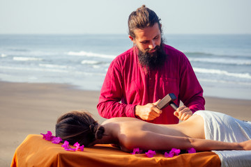 male master makes Thai massage Tok-sen spa therapy physiology by the sea ocean beach.Beautiful...