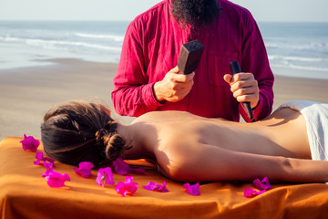 male master makes Thai massage Tok-sen spa therapy physiology by the sea ocean beach.Beautiful woman having a relaxing thai back massage with set for massage toksen,Body care relaxation resort © yurakrasil