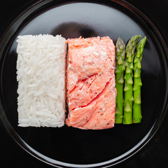 Rice salmon and asparagus on the black plate