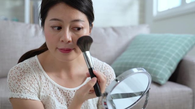 Young beautiful Asian woman professional beauty vlogger doing make up tutorial. beautiful girl using brush applying blush preparing in morning. female blogger applying makeup looking at mirror home