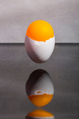 Eggshell stuck in the air above the table with an orange ball