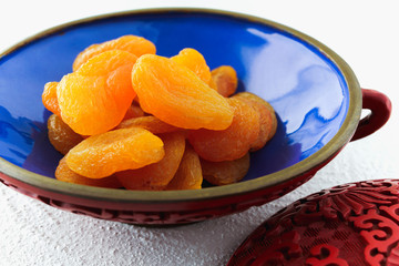 Dried apricot in a bowl close up with white background