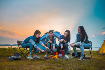 Friends of Young Asian women camping and cooking picnic together happy on weekend at sunset. - obrazy, fototapety, plakaty