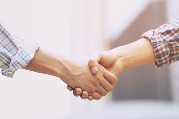 Obraz na płótnie Canvas Closeup of a business man hand shake between two colleagues greet , Represents Friendship is good,success, congratulations. outdoor of building background. copy leave space for text.