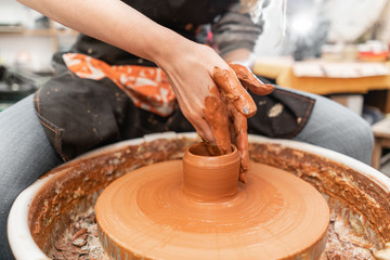 Craftsman hands making pottery bowl. Woman working on potter wheel . Family business shop sculpts pot from clay view top.
