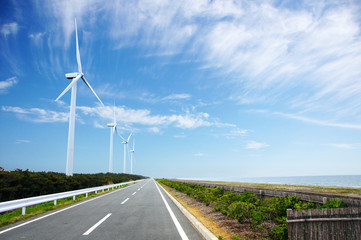 海岸沿いにある風力発電のための風車とまっすぐな道