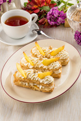 peach vanilla cream eclairs with tea cup on textile napkin