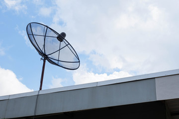A black satellite is on the iron roof under the light blue sky and cloud on clearly day