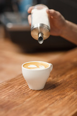 Barista pours sugar into the prepared cappuccino