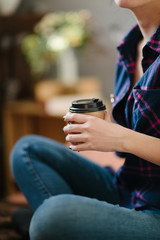 Girl holding hot cappuccino in a cardboard disposable cup