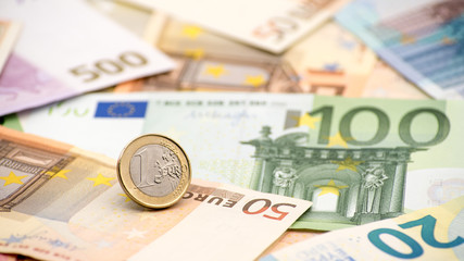 Closeup of a coin one euro with banknotes of different values. Cash money