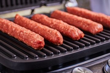 Serbian cevapi, cevapcici, Balkan minced meat kebab. Raw sausages lies ready to fry in grill. Close-up