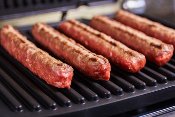 Serbian cevapi, cevapcici, Balkan minced meat kebab. Sausages cooking to grill. Close-up