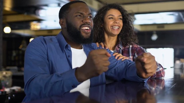 Multi-racial couple rooting for national team watching game, entertainment