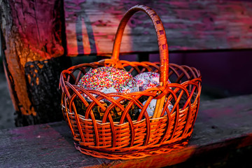 Fototapeta na wymiar Easter basket with cake on wooden surface. Holiday cookies with bright icing top for spring celebration. Russian kulich in beautiful light of the sunset. Traditional Easter treat – sweet cooking